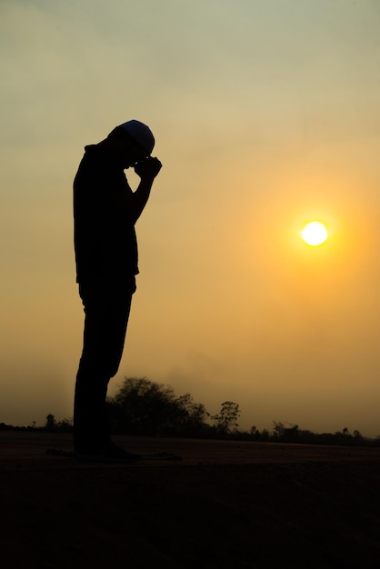 Photo silhouette young asian muslim man praying on sunsetramadan festival concept