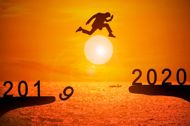 Silhouette of young businessman jumping from 2019 to 2020