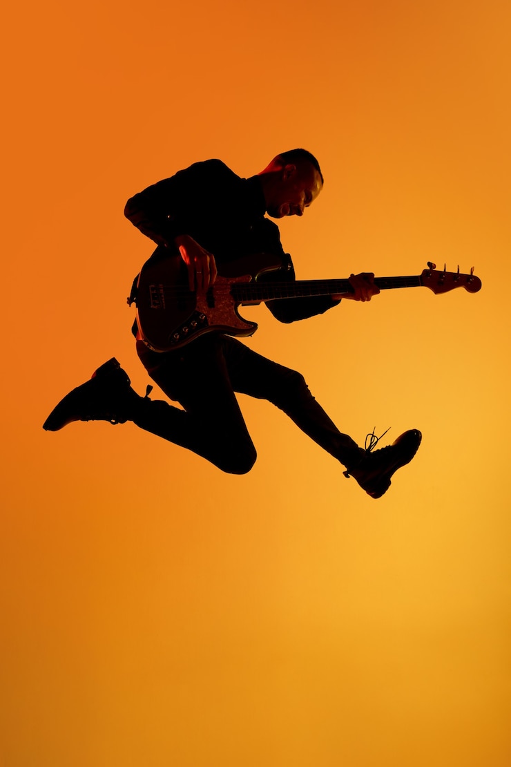 Photo silhouette of young caucasian male guitarist isolated on blue-pink gradient studio in neon light