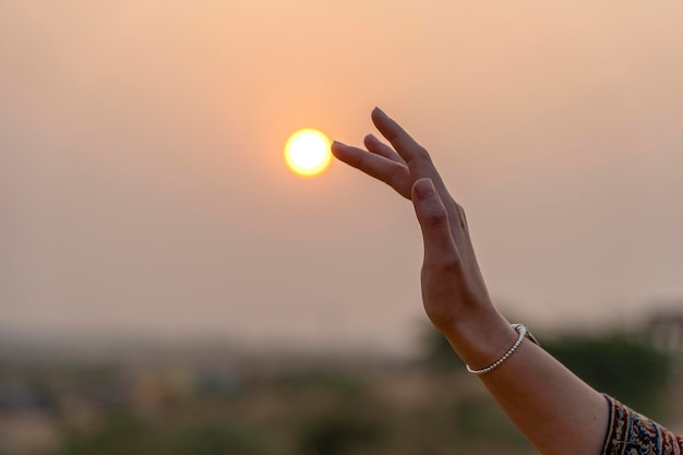 Silhouette of young girl holding the sun in hand during sunset\
close up