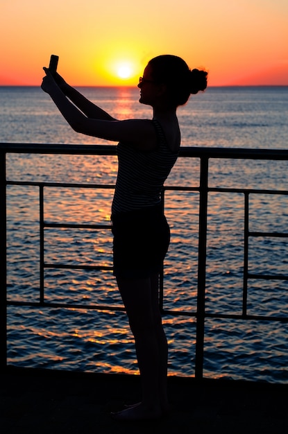 Silhouette of a young girl at sunset. Twilight, waves. Girl maki