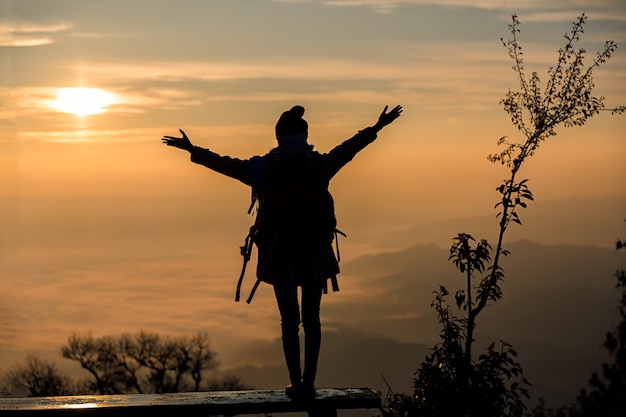 Photo silhouette of a young girl on the top of the mountain