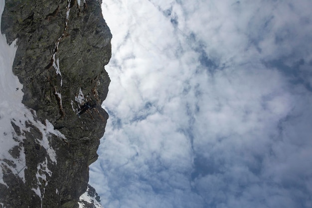 Silhouette of young man abseiling down from a snowy cliff Climber rappelling from a white rock