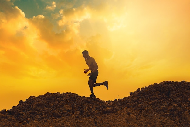 Silhouette of young man runner running trail at the top of mountain Healthy and lifestyle concept