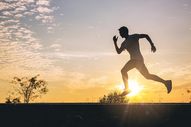 Photo silhouette of young man running sprinting on road. fit runner fitness runner during outdoor workout