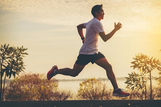 Silhouette of young man running sprinting on road. Fit runner fitness runner during outdoor workout