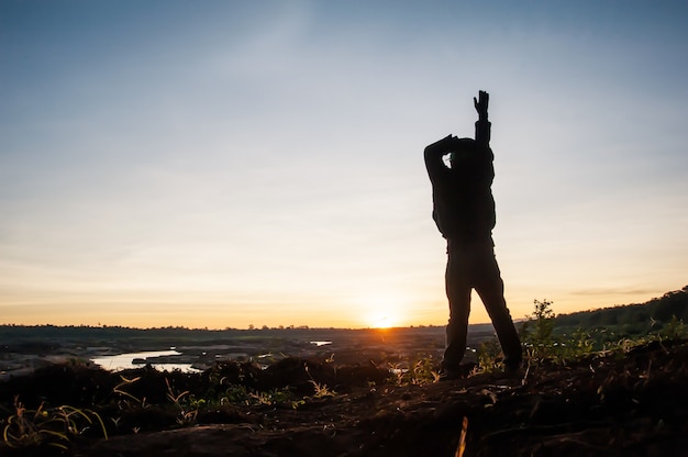 Silhouette young man on sunrise with trekking