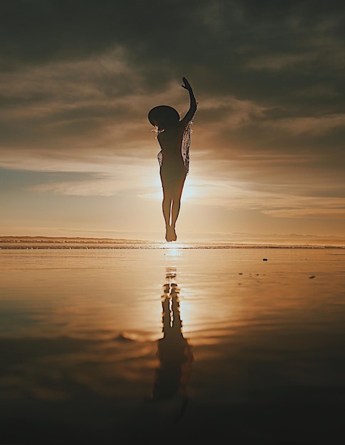 Photo silhouette young woman jumping at beach against sky during sunset