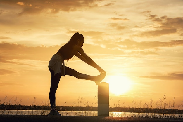 Silhouette Young woman practicing Meditation yoga onÃÂÃÂ the beach at sunset