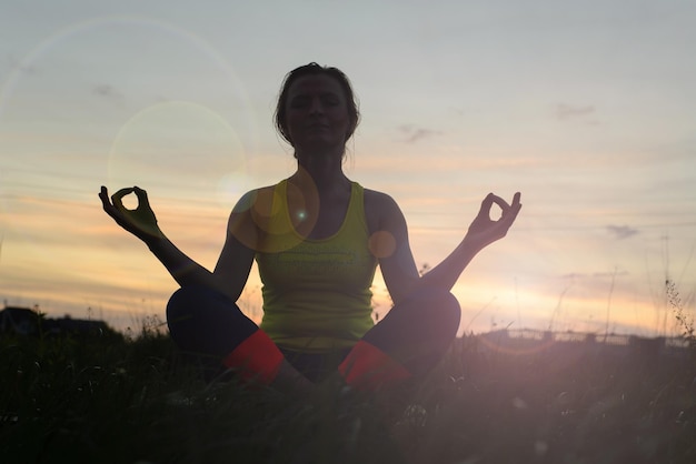 Silhouette young woman practicing yoga at backyard