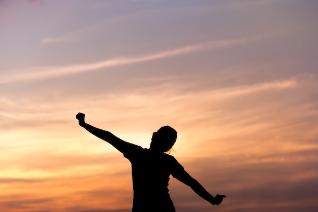 Silhouette young woman relaxing in sunset sky outdoor. 