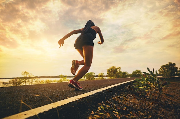 Silhouette of young woman running sprinting on road fit runner\
fitness runner outdoor workout