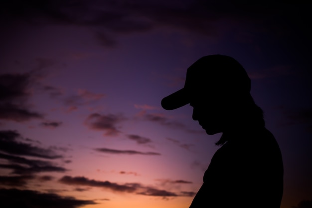 Foto siluetta della giovane donna che sta contro il tramonto con il bello cielo