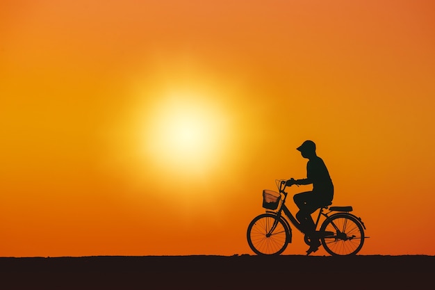 Silhouette of a young woman standing sadly looking at the sky at sunset