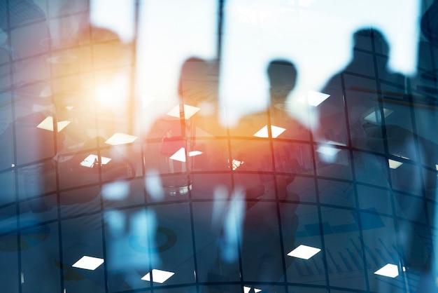 Silhouette of young workers in the office with statistic worksheets concept of teamwork and business double exposure