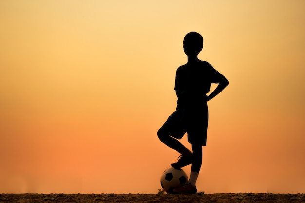 Silhouetten van Aziatische jongen is voetballen.