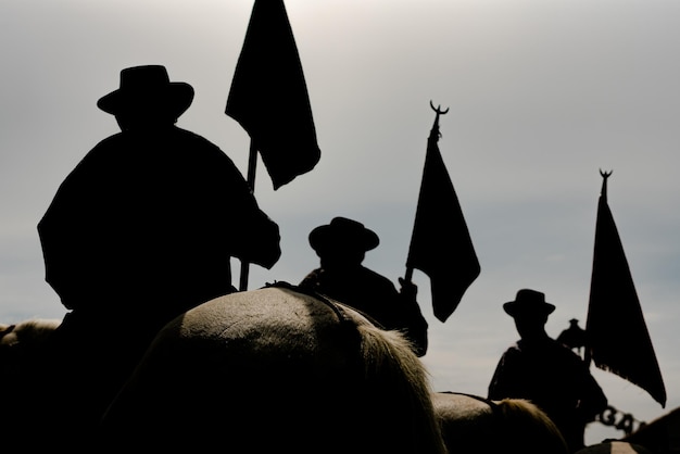 Foto silhouetten van drie bewakers met hun vlaggen tijdens de processie in saintes maries de la mer