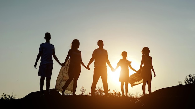 Silhouetten van familie houden handen vast op heuvel onder heldere hemel