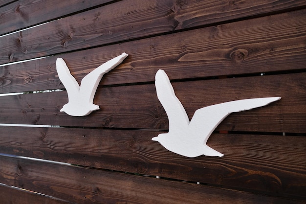 Silhouetten van figuren van kunstmatige meeuwen op houten achtergrond Paar vogels vliegen naar het zuiden