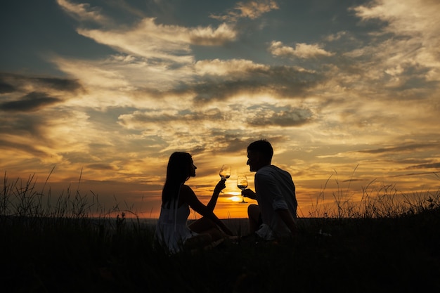 Silhouetten van jonge man en vrouw op vakantie of huwelijksreis bij geweldige avondrood.