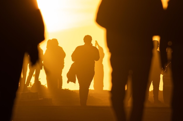 Silhouetten van mensen tegen de achtergrond van een oranje heldere zonsondergang loopt een persoon langs de weg