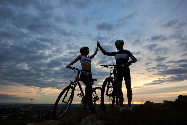 Silhouetten van twee fietsers na het rijden van fietsen.