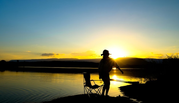 Silhouetten van vrouwen staan op het meer bij zonsondergang, reservoir amphoe wang saphung loei thailand