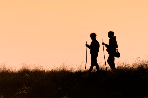 Silhouetten van wandelaars met rugzakken die zonsondergang van mening vanaf bovenkant van een berg genieten