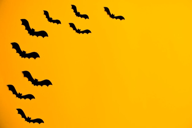 Silhouetten van zwarte vleermuizen gemaakt van papier op een oranje achtergrond. halloween concept