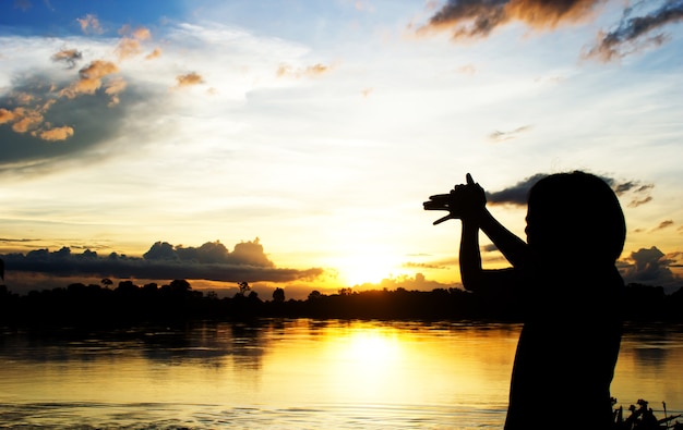 Silhouetten Vrouwen maken hond teken door haar hand over mooie zon