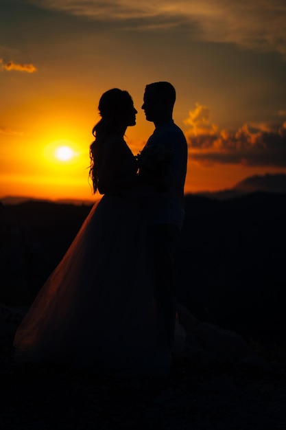 夕暮れの山で抱きしめ合っている新郎と新婦のシルエット