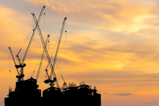 Silhouettes of building construction site and construction crane