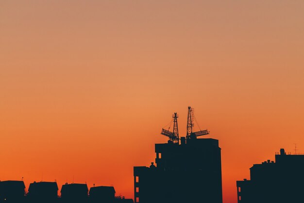 Silhouettes of buildings on orange background of sunset sky