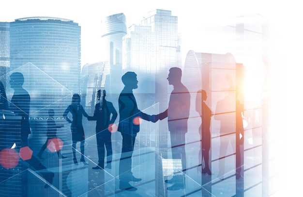 Photo silhouettes of business people shaking hands and discussing work over cityscape background with skyscraper. toned image double exposure