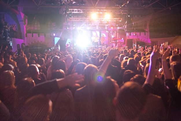 The silhouettes of concert crowd in front of bright stage lights. Concert of an abstract rock band