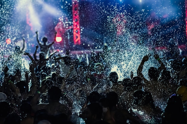 Silhouettes of concert crowd in front of bright stage lights, pool party