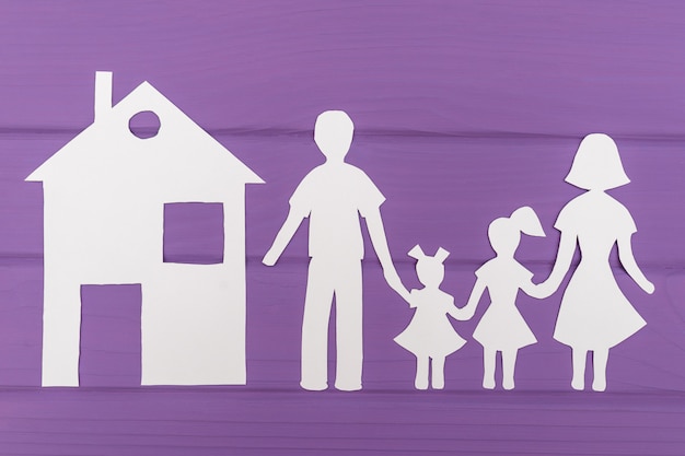 The silhouettes cut out of paper of man and woman with two girls, house near