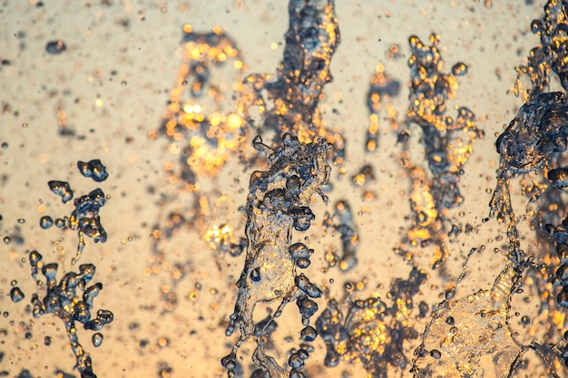 Silhouettes of drops falling water fountain against the backdrop of the setting sun