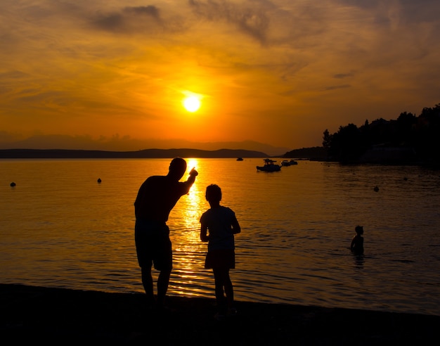 Silhouettes of  father and little daughter on the beach at sunset