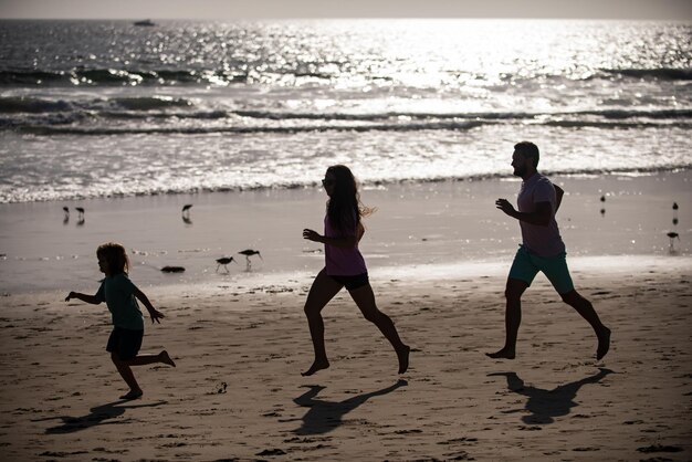 Foto sagome di famiglia fitness in esecuzione vicino al mare