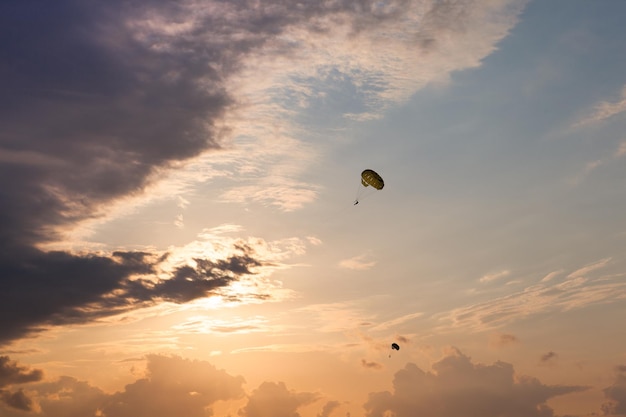 黒海の上の夕焼け空に飛んでいるパラシュートのシルエット