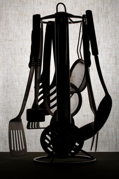 Silhouettes of kitchen utensils on the holder on a gray background