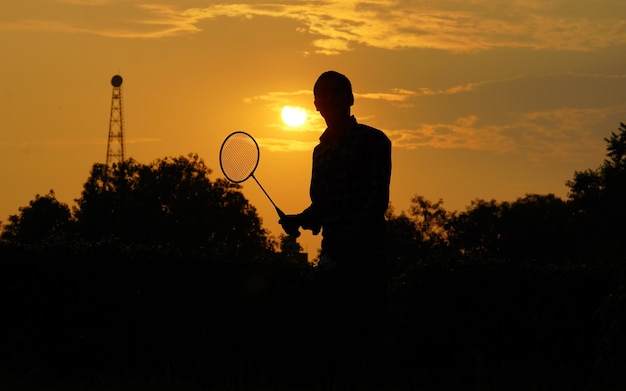 Silhouettes man houdt de shuttle en het badmintonracket vast