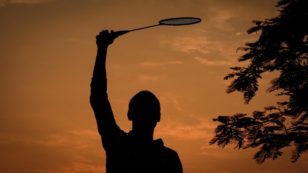 Silhouettes man tiene in mano la racchetta da badminton