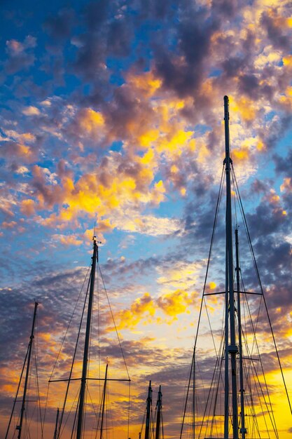 Silhouettes of the masts of sailing yachts on a sunset background