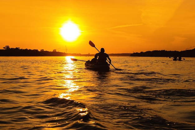 Silhouettes of people in boat at sunset Man and woman ride boat on river Small family trip