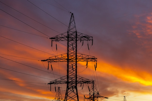 Silhouettes of power lines on a sunset. Bright orange urban sunset