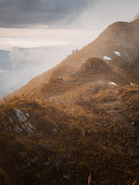 自由を楽しんでいる丘を手をつないで歩いている2人のシルエットロマンチックなカップルの散歩渓谷に霧のある山脈の印象的なパノラマ
