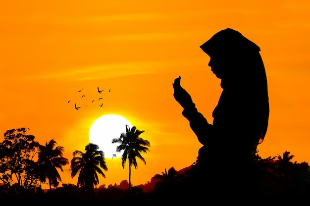 Silhouettes of a women praying during sunset