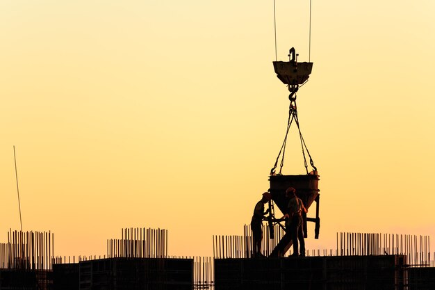 Silhouettes of workers on the construction of a skyscraper against the backdrop of the sunset sky